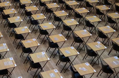 Rows of small exam desks in a school hall